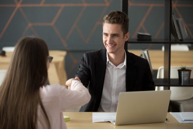 Photo of man and woman shaking hands illustrates blog: "Hiring Bias: What It Is and How to Reduce It"