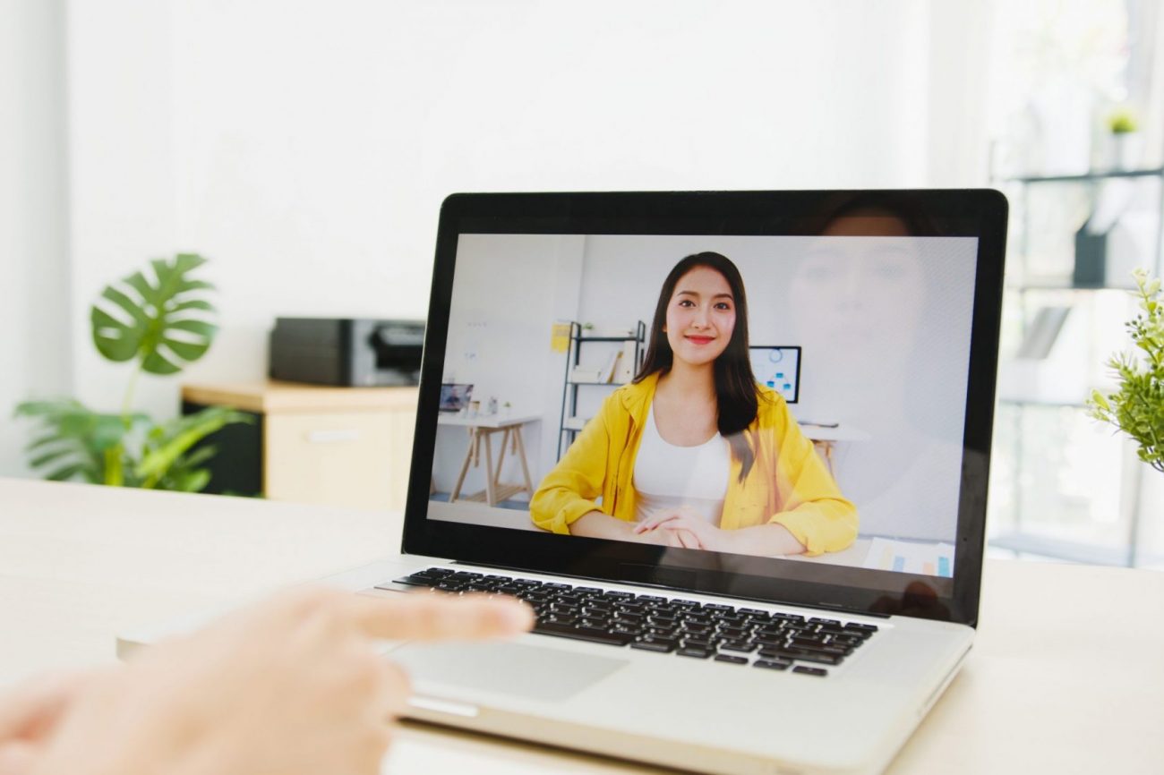 Photo of woman smiling on computer screen illustrates blog: "15 Questions You Should Ask When Hiring for a Remote Position"