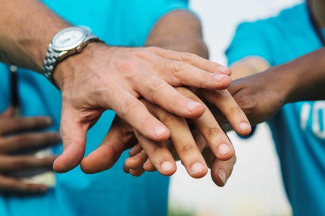 Photo of team putting hands together illustrates blog: "Background Checks for Volunteers"