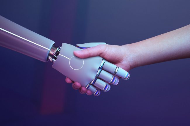 Photo of human shaking robot hand illustrates blog "How Can Artificial Intelligence Help Recruiters and Hiring Managers?"