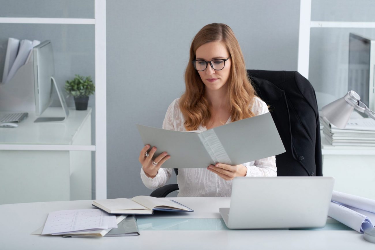 Woman looking at open folder illustrates blog "Are Background Checks Public Record?"