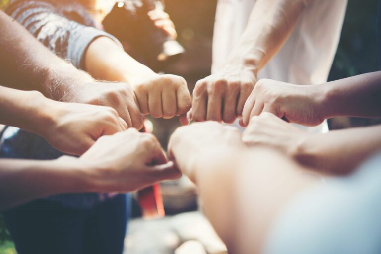 Photo of group of people touching fists.
