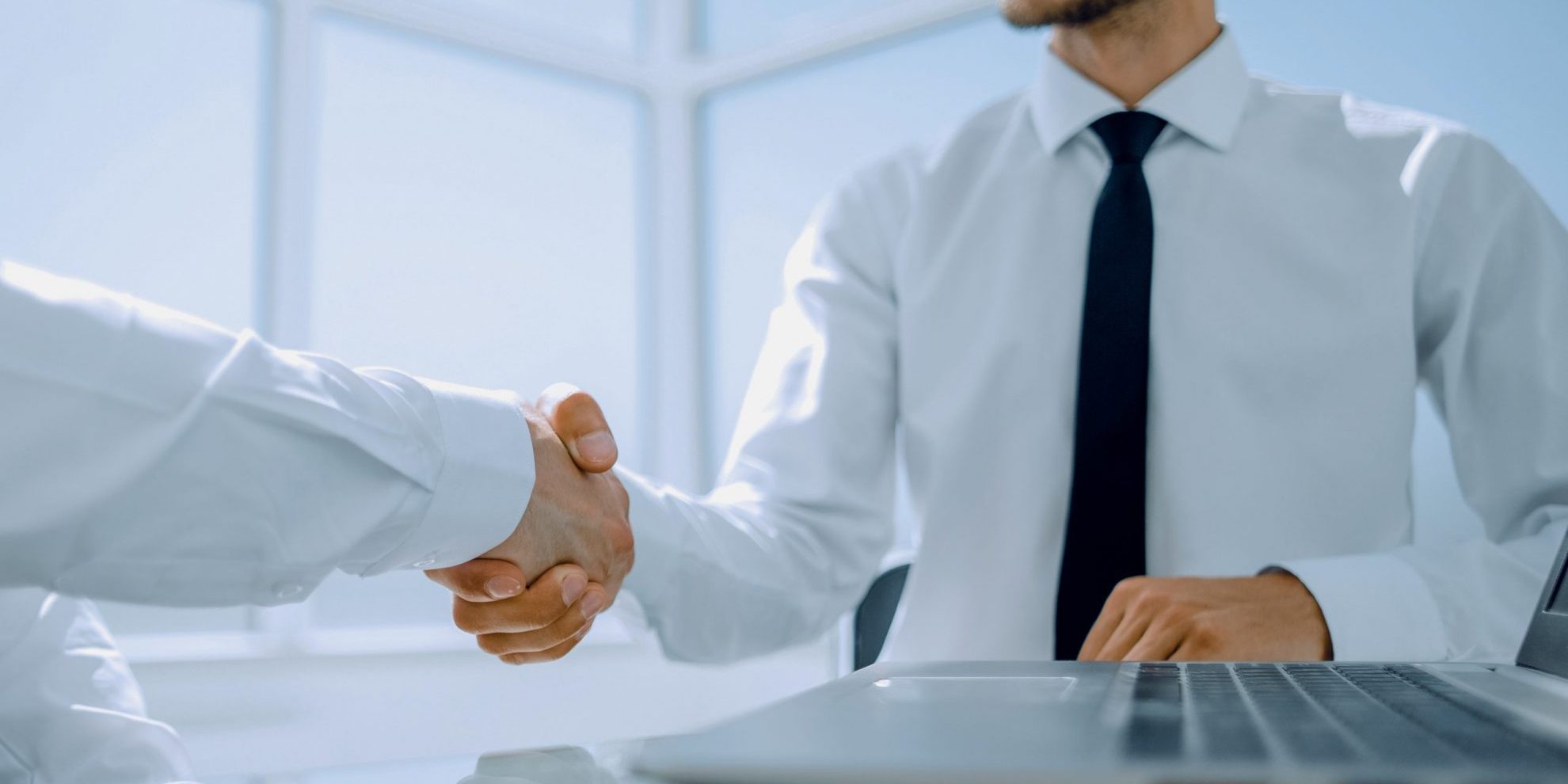 Two men shaking hands illustrate blog "Background Check vs Consumer Report: What Is the Difference?"