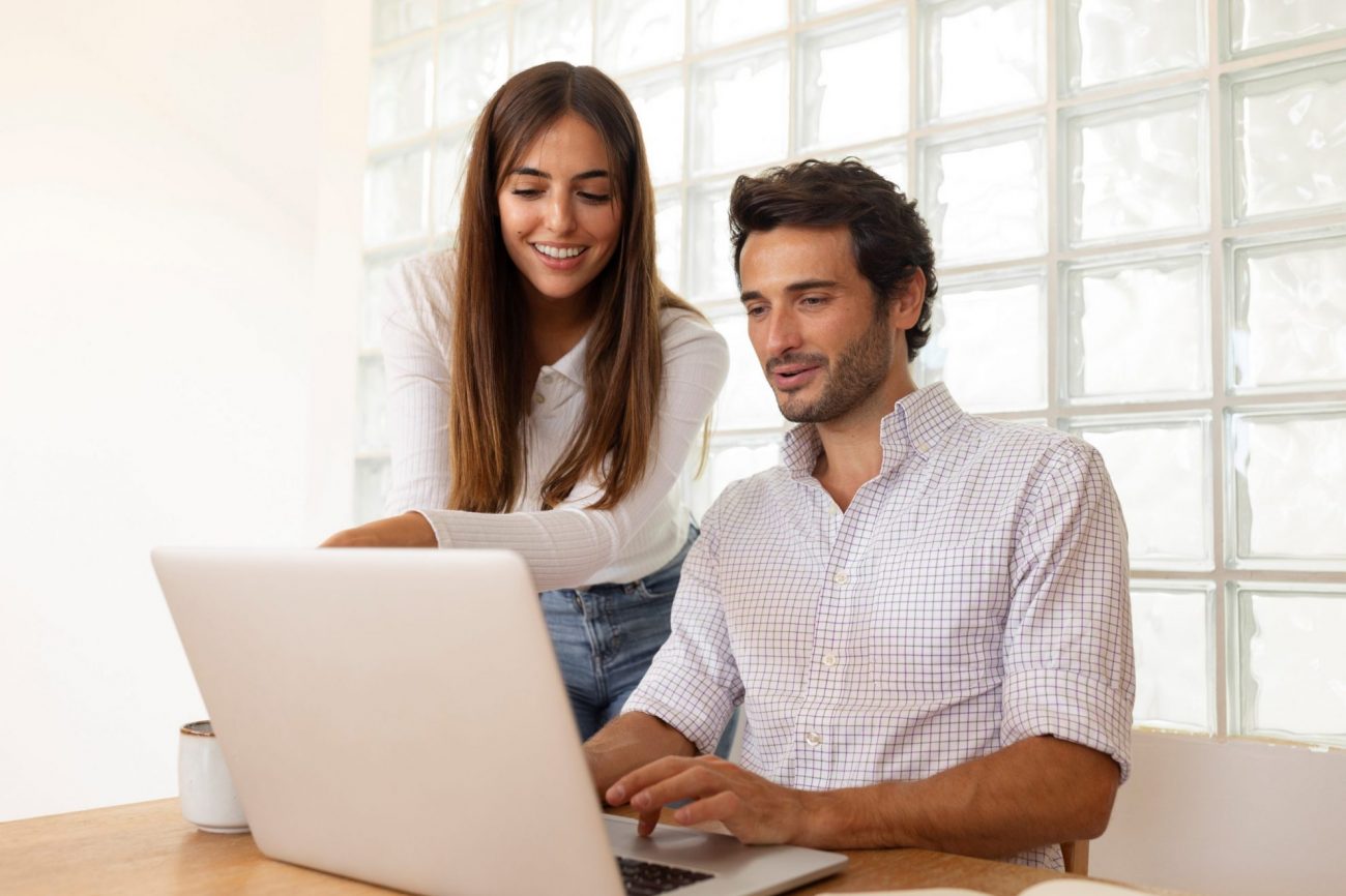 Woman and man looking at laptop illustrate blog "4 Ways Recruiters Can Use ChatGPT"