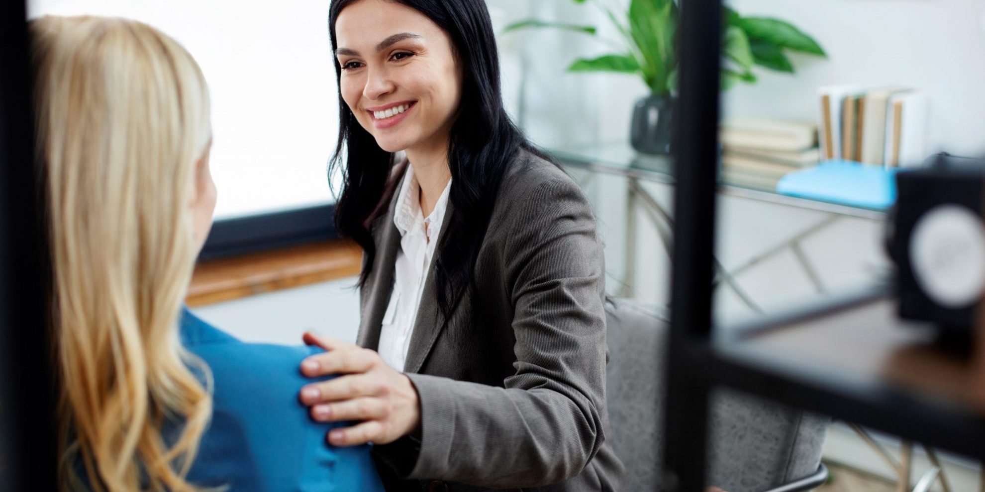 Woman with her hand on the shoulder of another woman seen from behind illustrates blog "What Is Skills-First Hiring?"