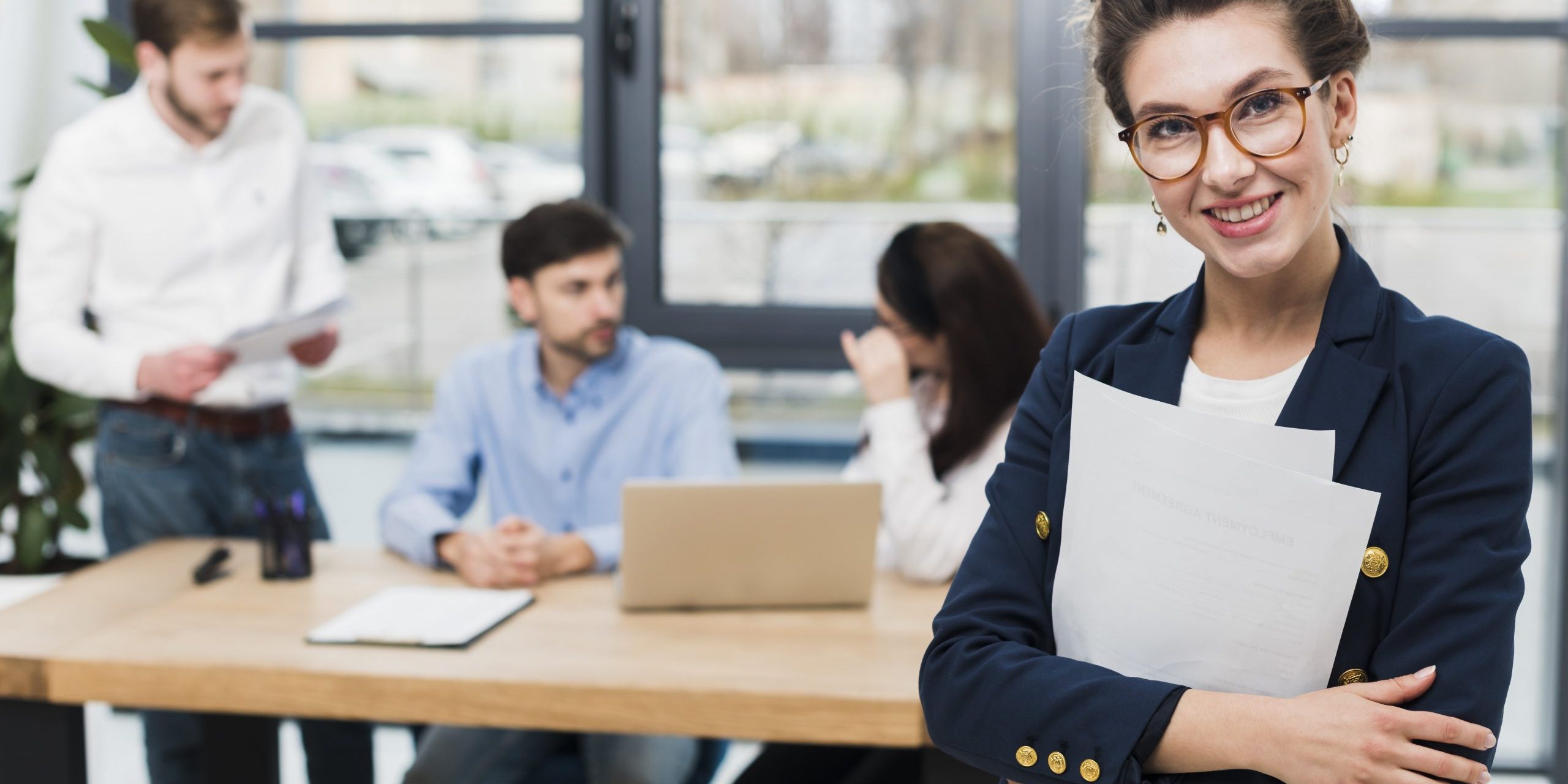 resume-jobs-FP Woman in business attire with people sitting at desk in the background illustrates blog "Will a Background Check Show All My Jobs?"
