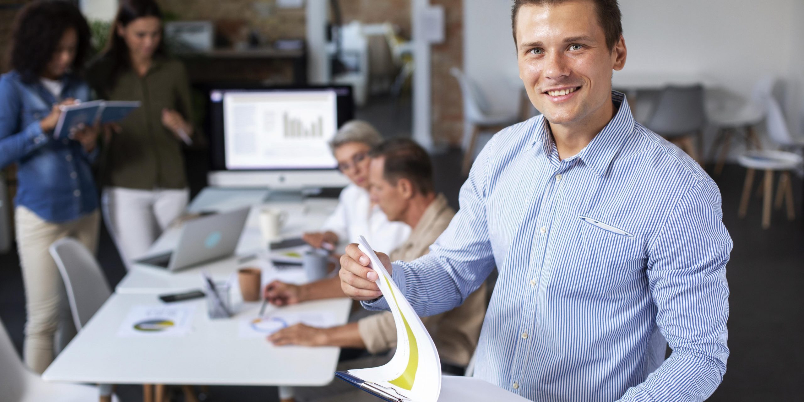 employee-office-fp Man in office holding clipboard illustrates blog "Internal Gigs and Background Screening"