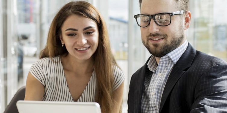 Woman and man looking at tablet illustrate blog "Background check vs Reference Check: "What Is the Difference?"