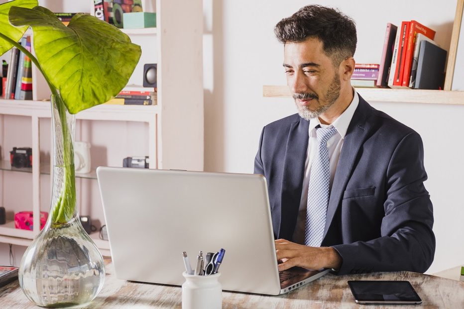 man-office-laptop-freepik Man in office typing on laptop illustrates blog "5 Background Screening Trends You Need To Know"