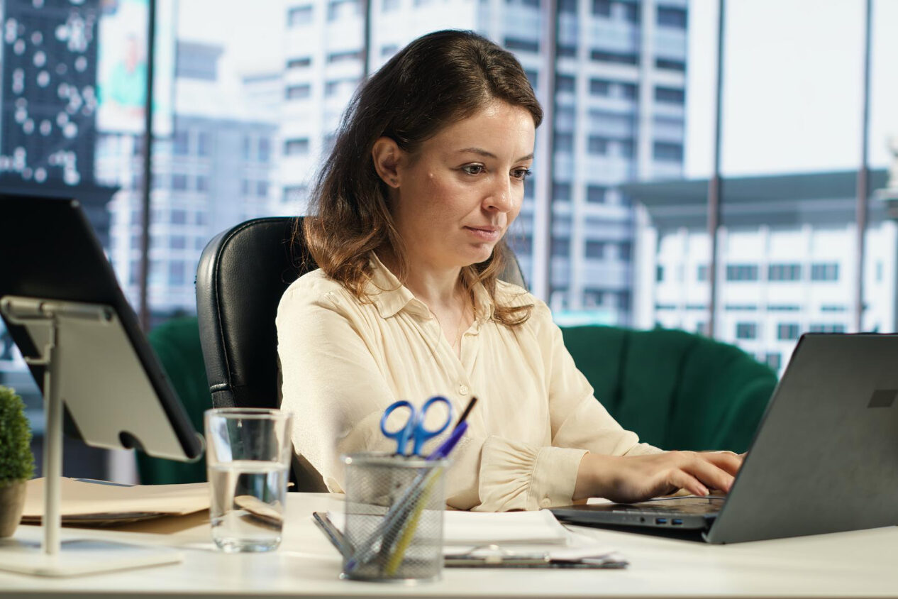 124877 HR manager handling multi-state hiring compliance documents on laptop